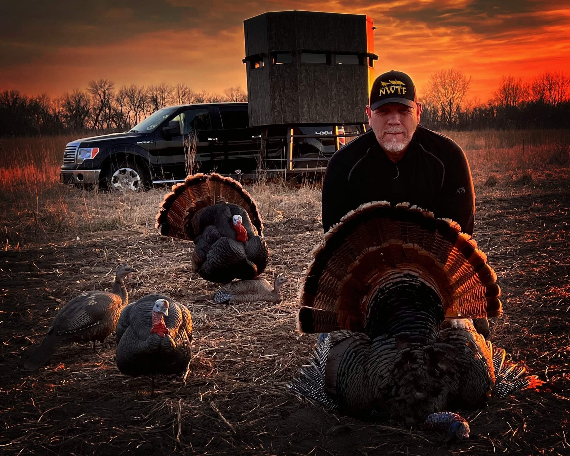 Hunter with spring turkey at sunrise in front of a ground blind
